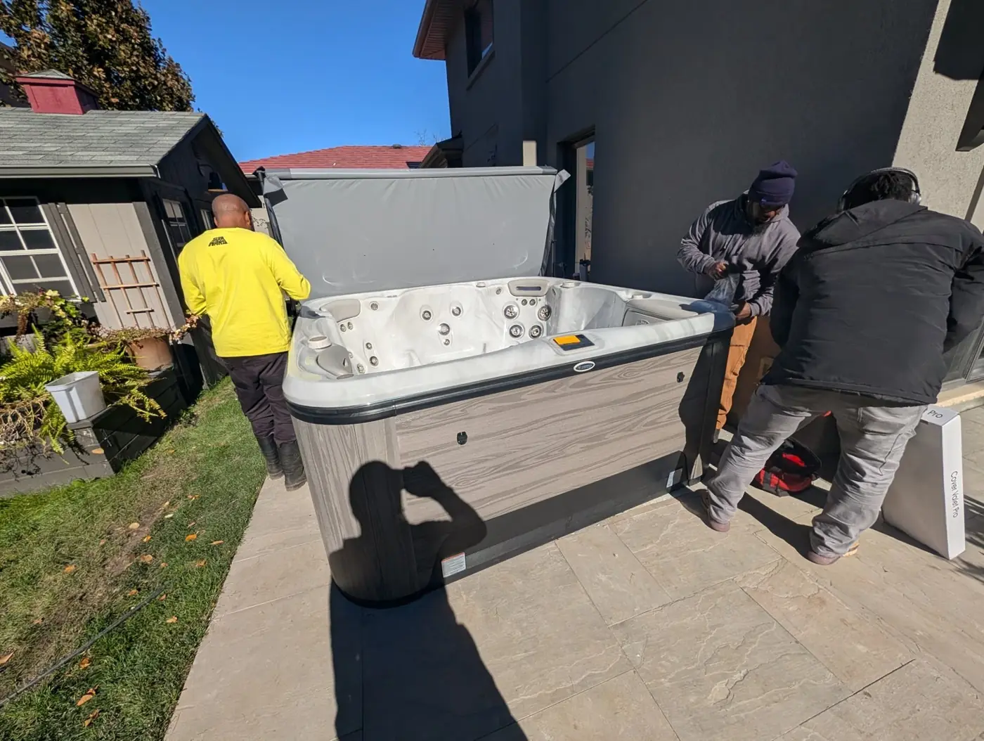 CPS crew carrying a hot tub on its side down a narrow side yard in Scarborough