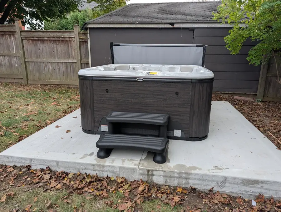 Hot tub set on a new concrete pad with steps in an Aurora backyard
